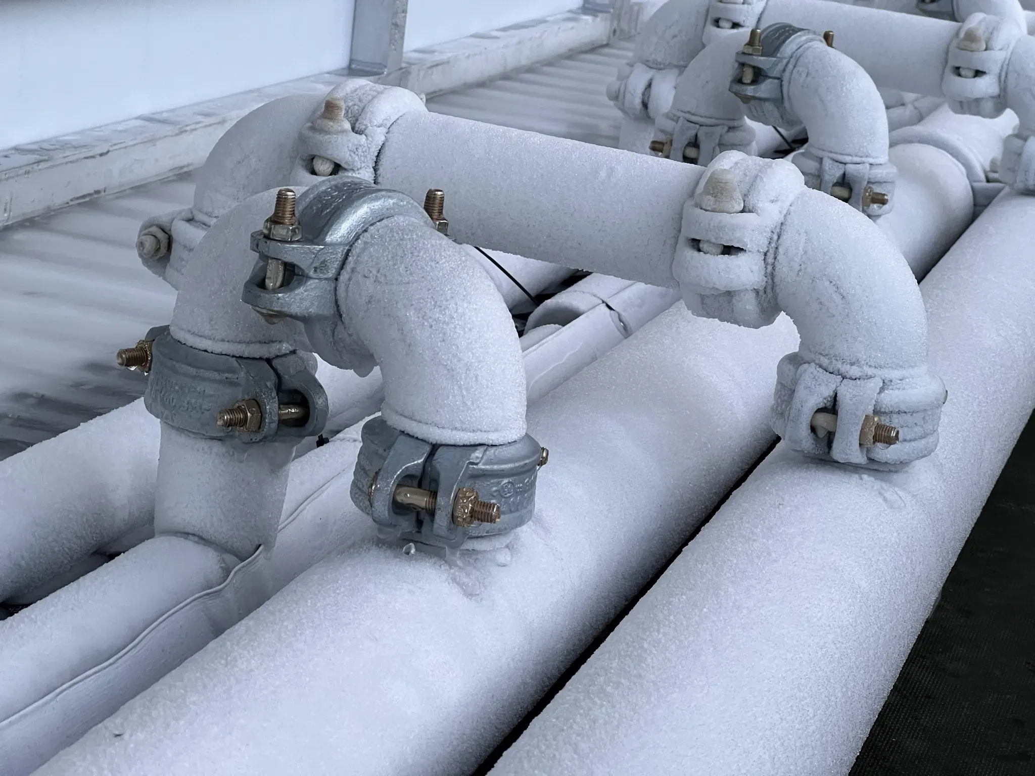 Frosted cooling pipework and couplings at the edge of a rink
