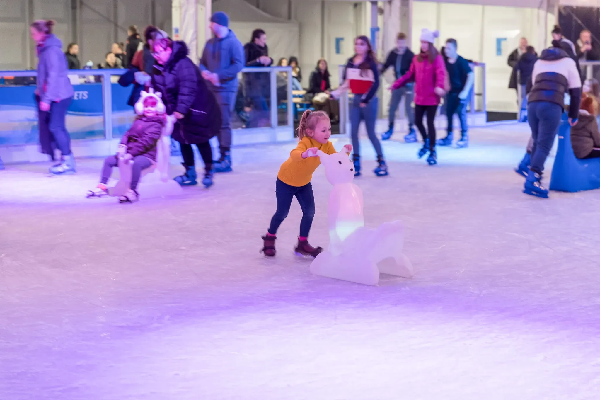 A young girl taking her first steps with a skating aid in Corby