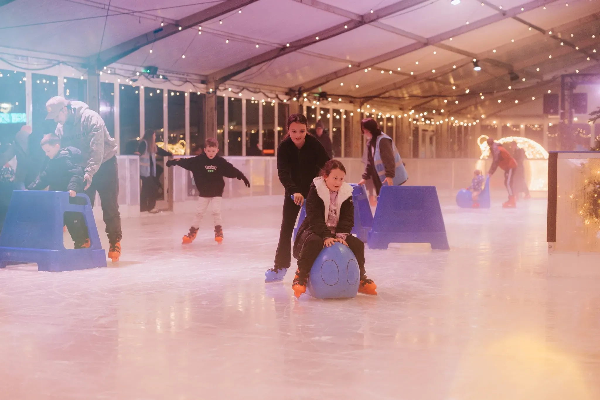 Families skating with frame and seal skating aids at Willen On Ice