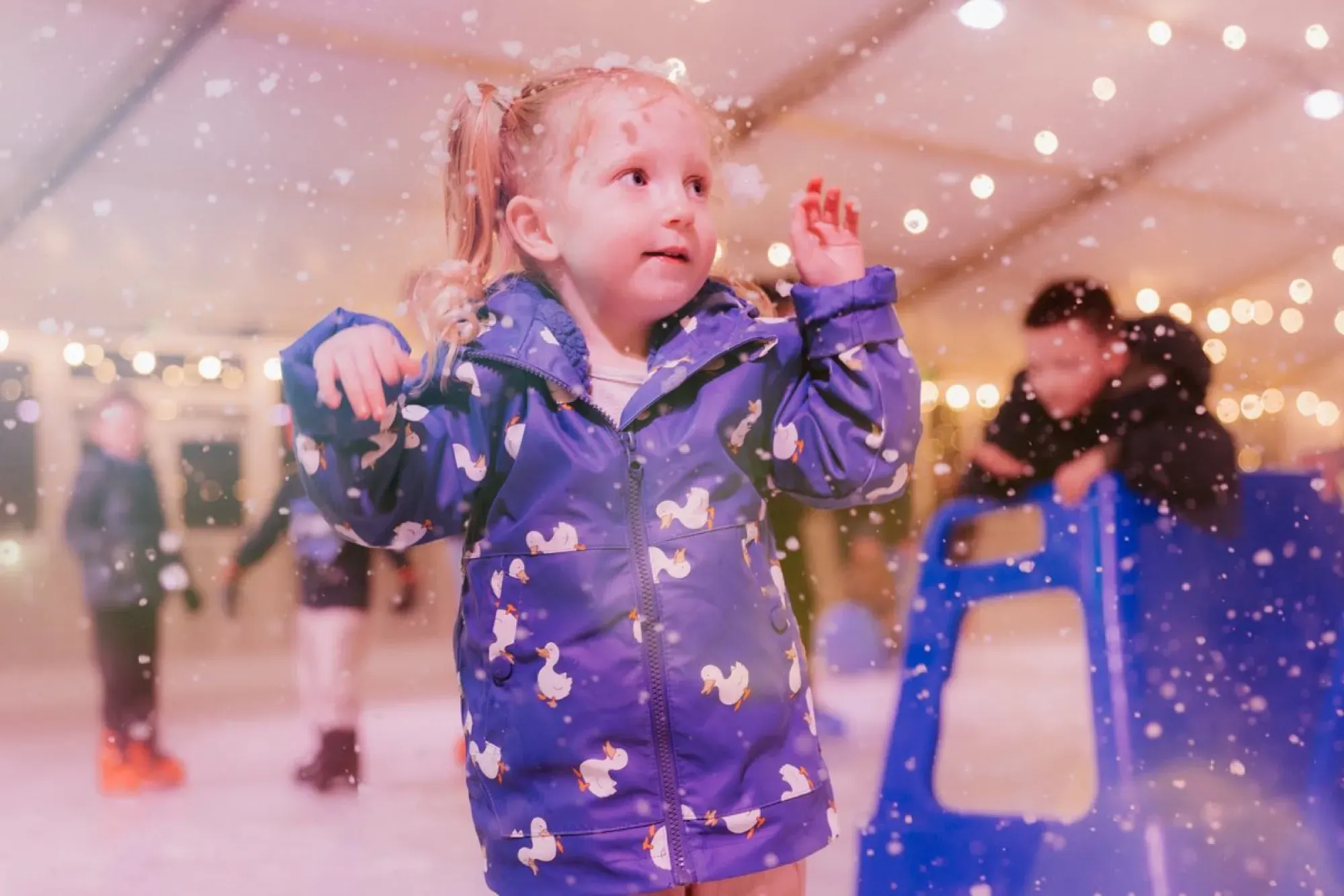 A young skater laughing under falling snow at Willen On Ice