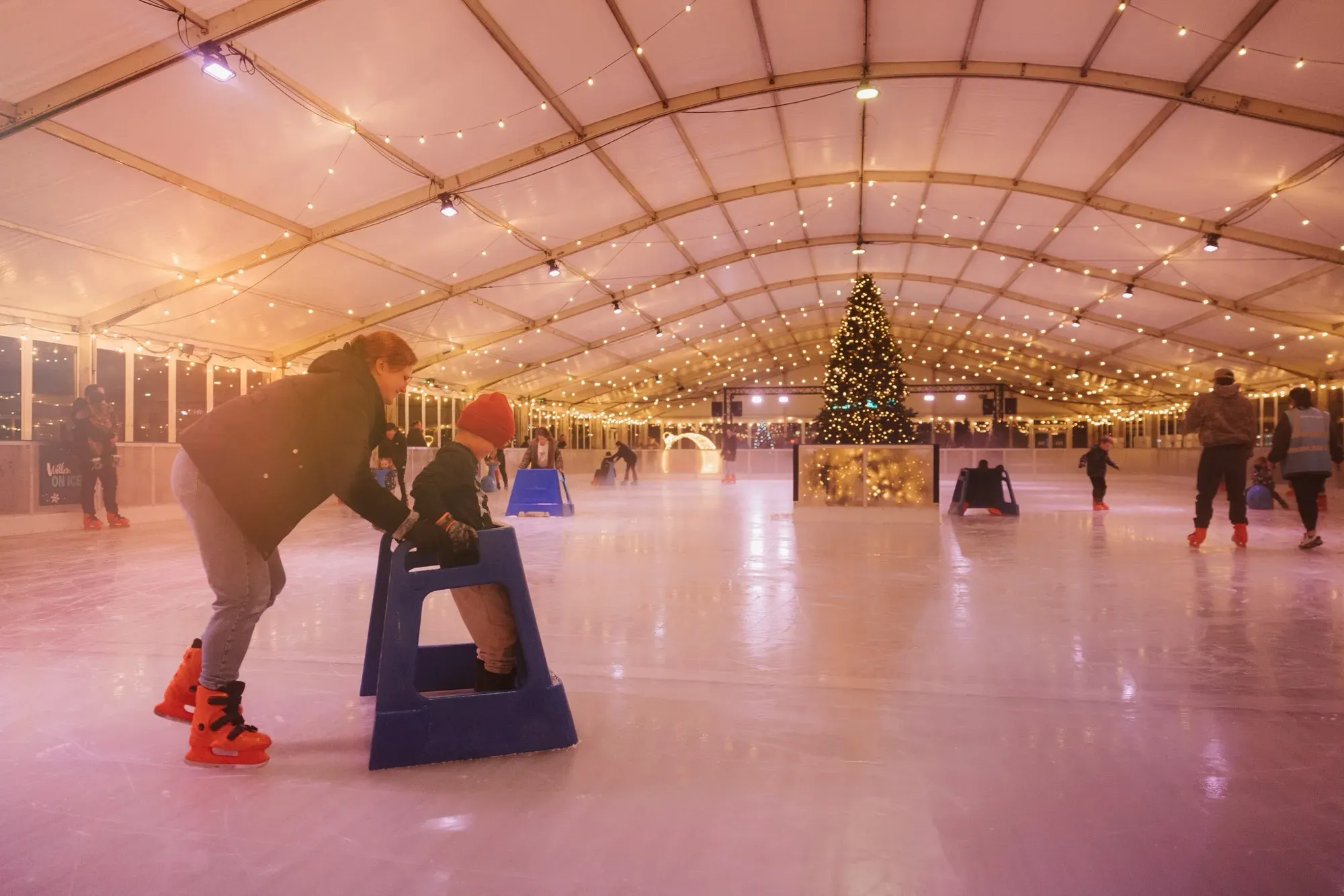 Skaters beside a Christmas tree inside the Willen On Ice marquee