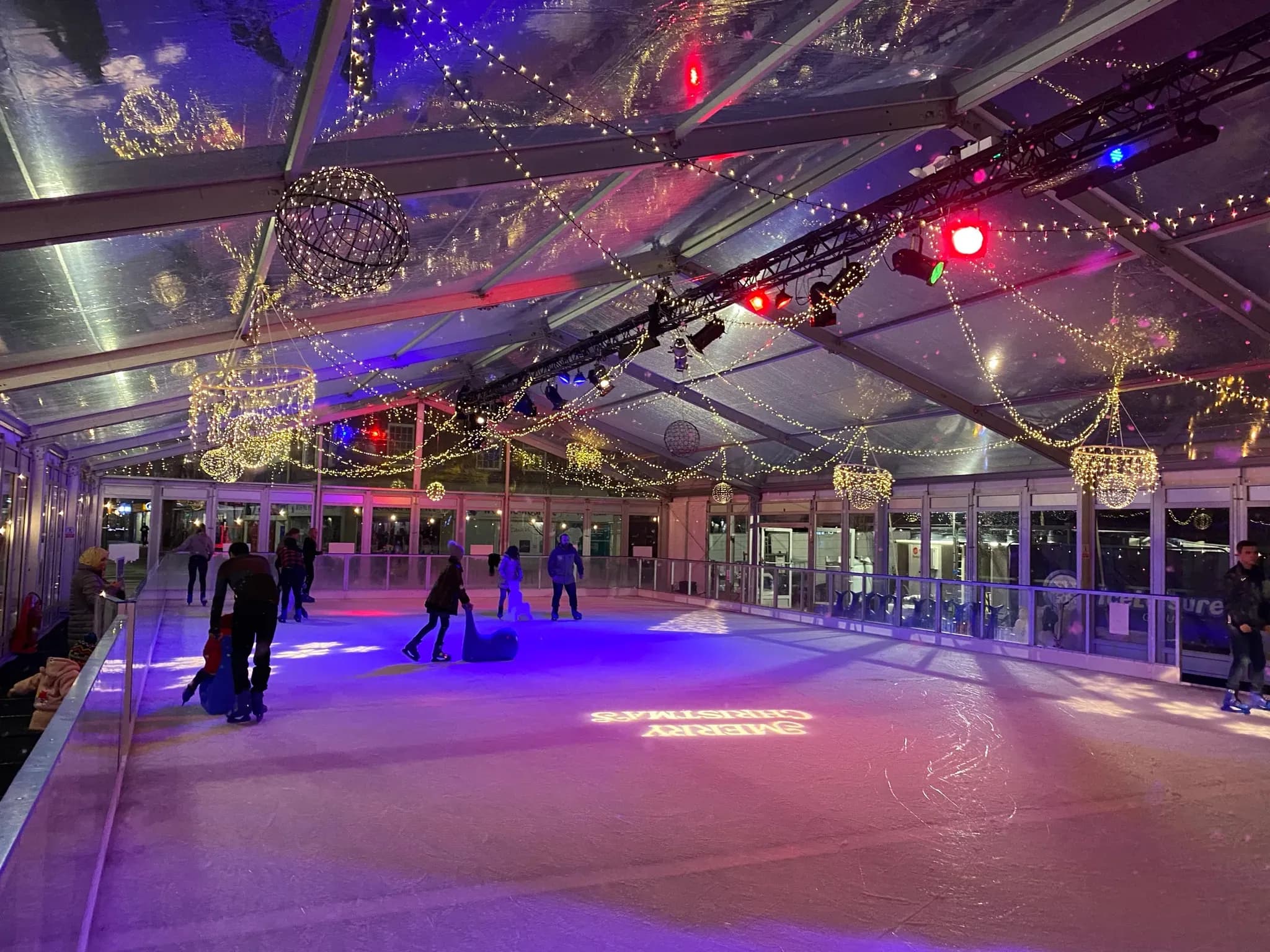 The Woking rink at night under a clear marquee roof hung with festoon lights